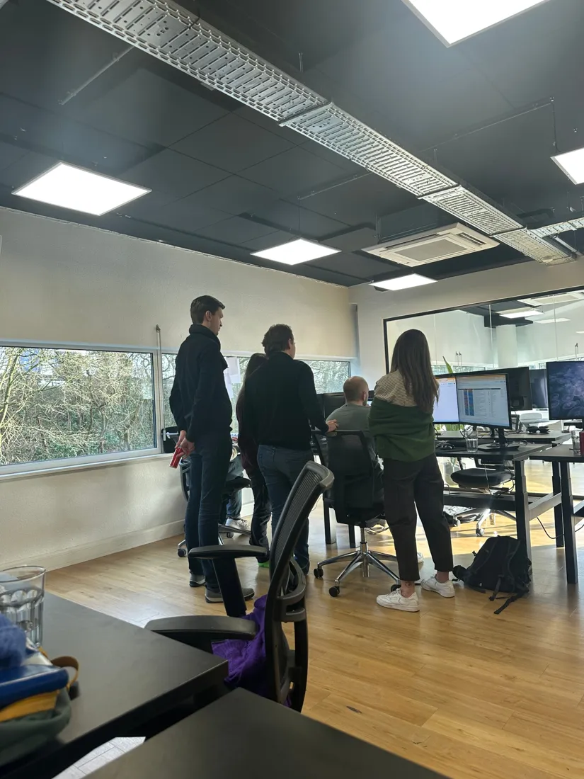 A group of developers gathered around a screen